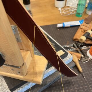 ステッチングポニーに挟み、鉢に巻く革のベルトを手縫いしているところ